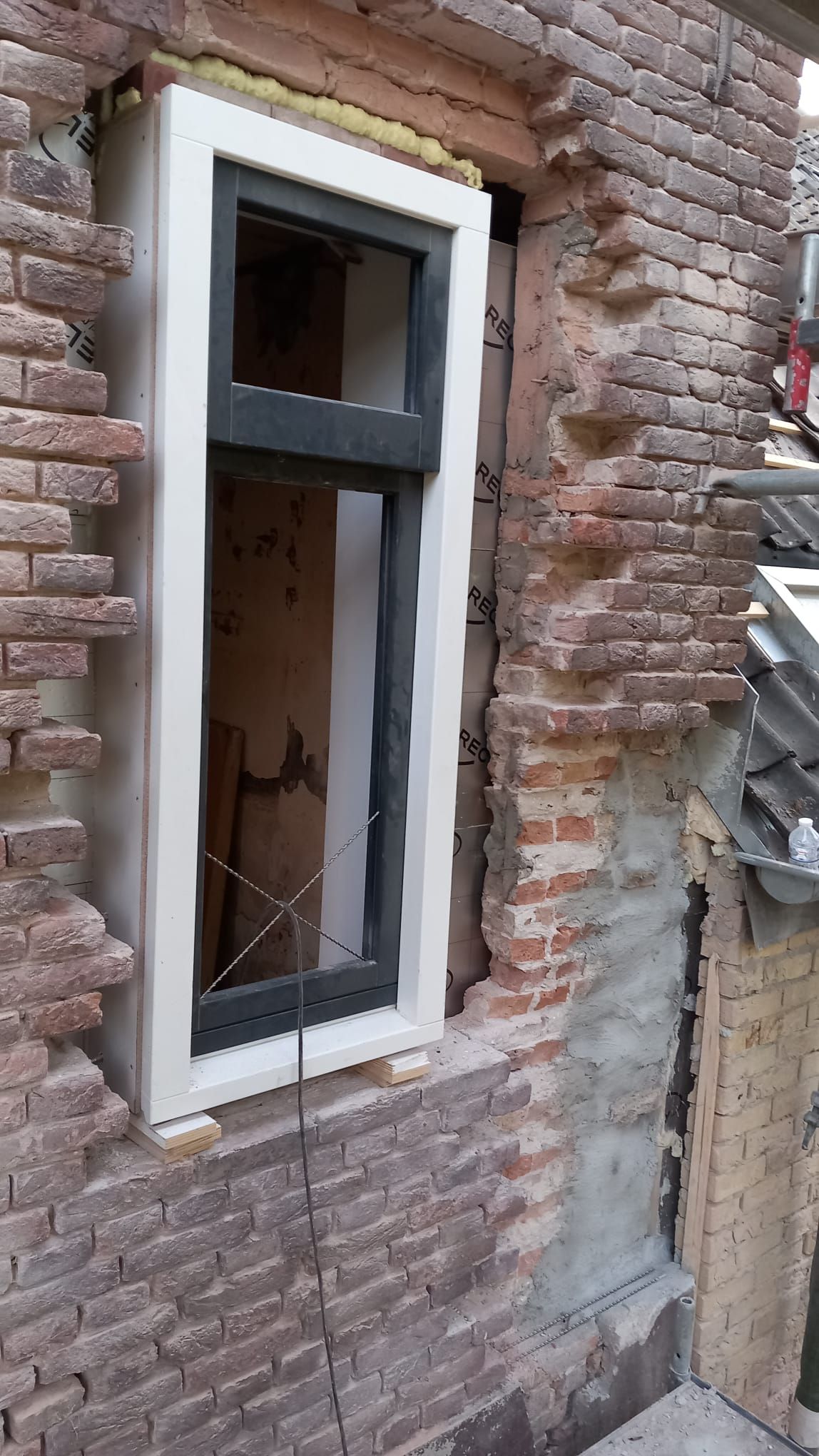 Kozijn in een bakstenen gevel met het omliggende metselwerk in bewerking.