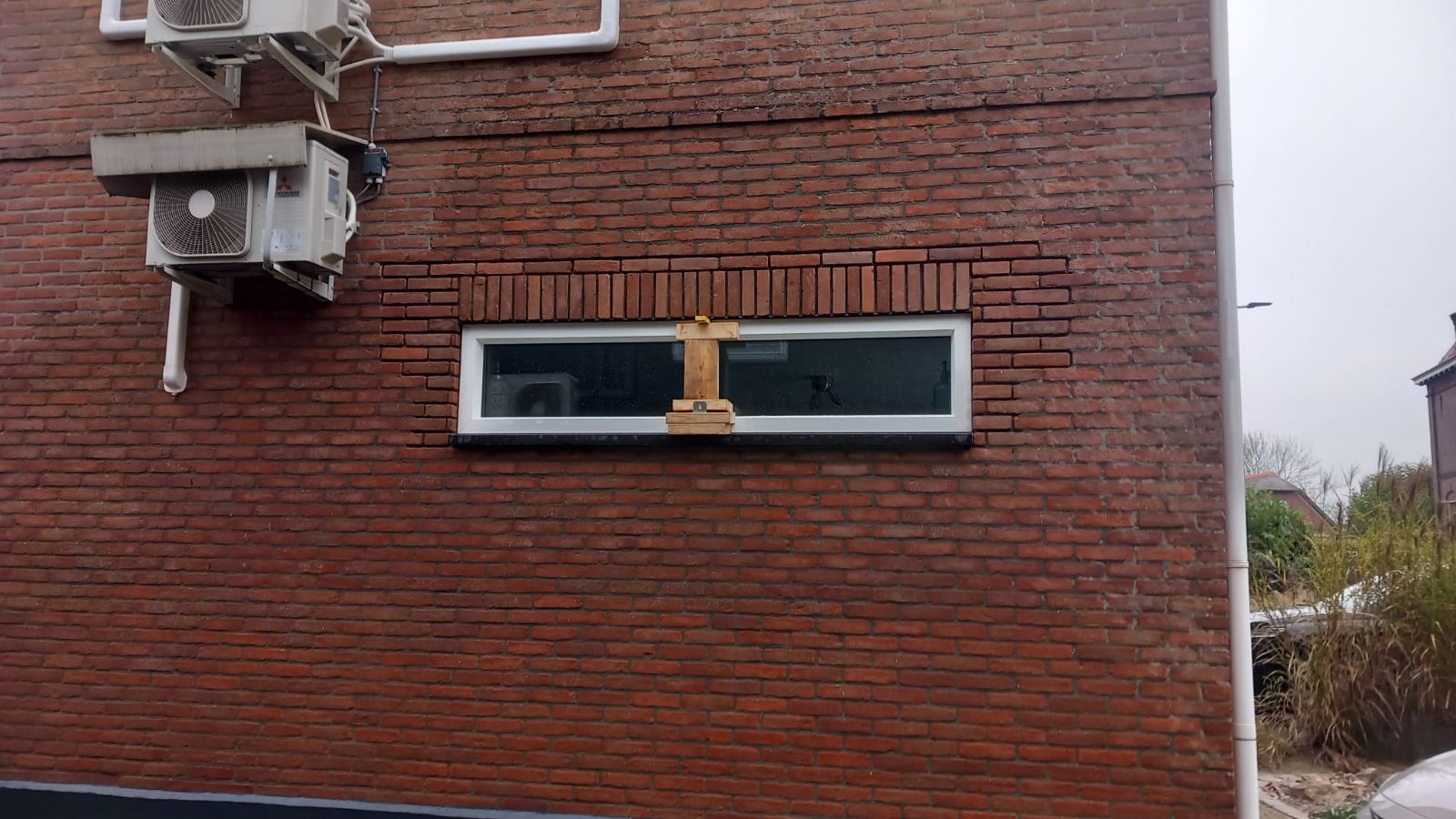 Lang smal kozijn in een bakstenen gevel, met het metselwerk erboven dichtgezet.