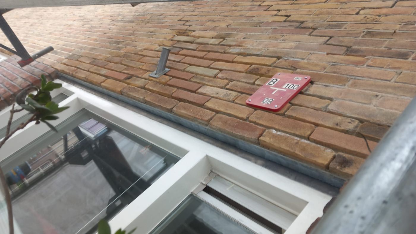 Metselwerk boven een kozijn met een nieuw geplaatste latei, gezien vanaf de begane grond.