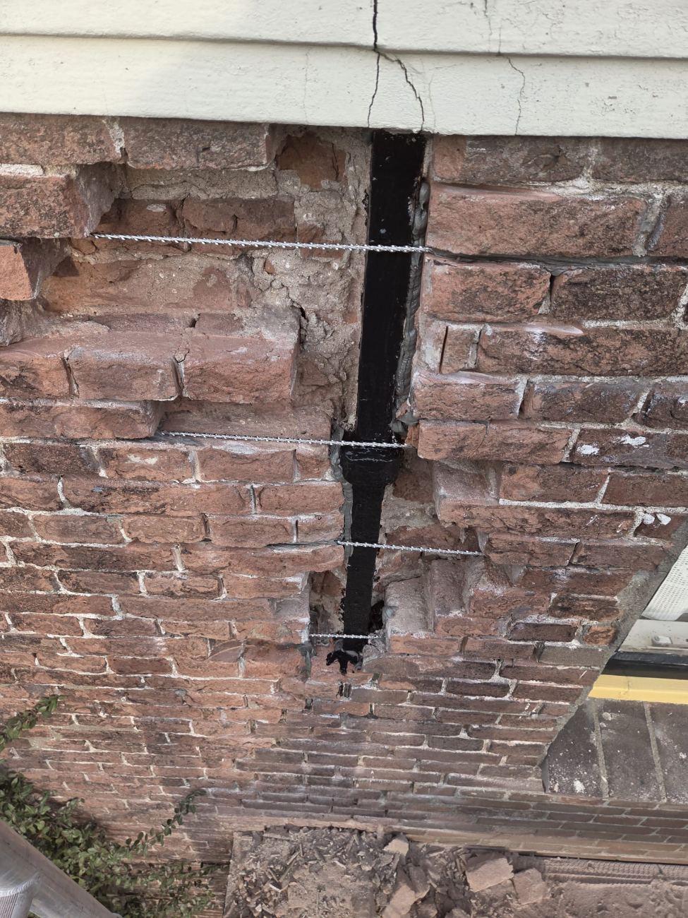 Close-up van scheurherstel in een bakstenen muur, met RVS spiraalankers aangebracht over de scheur