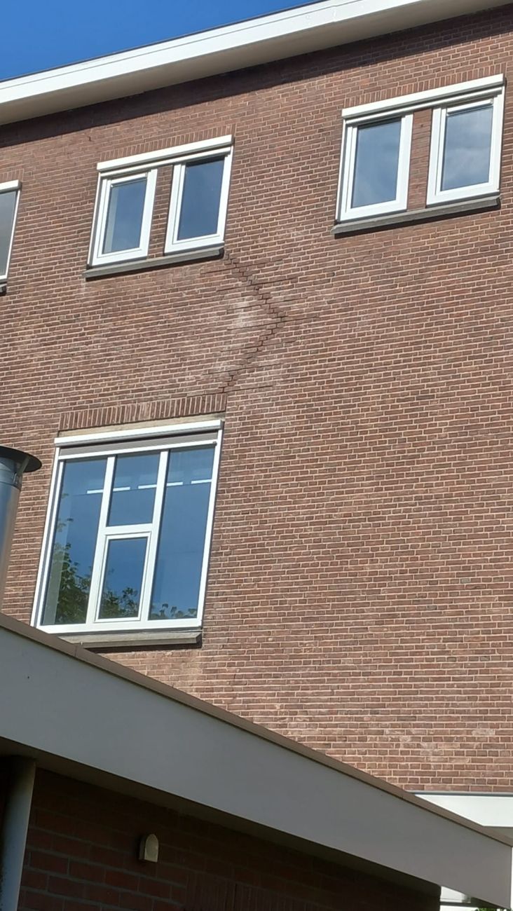 Diagonale trapsgewijze scheur in een bakstenen gevel, na herstel weggewerkt in het voegwerk
